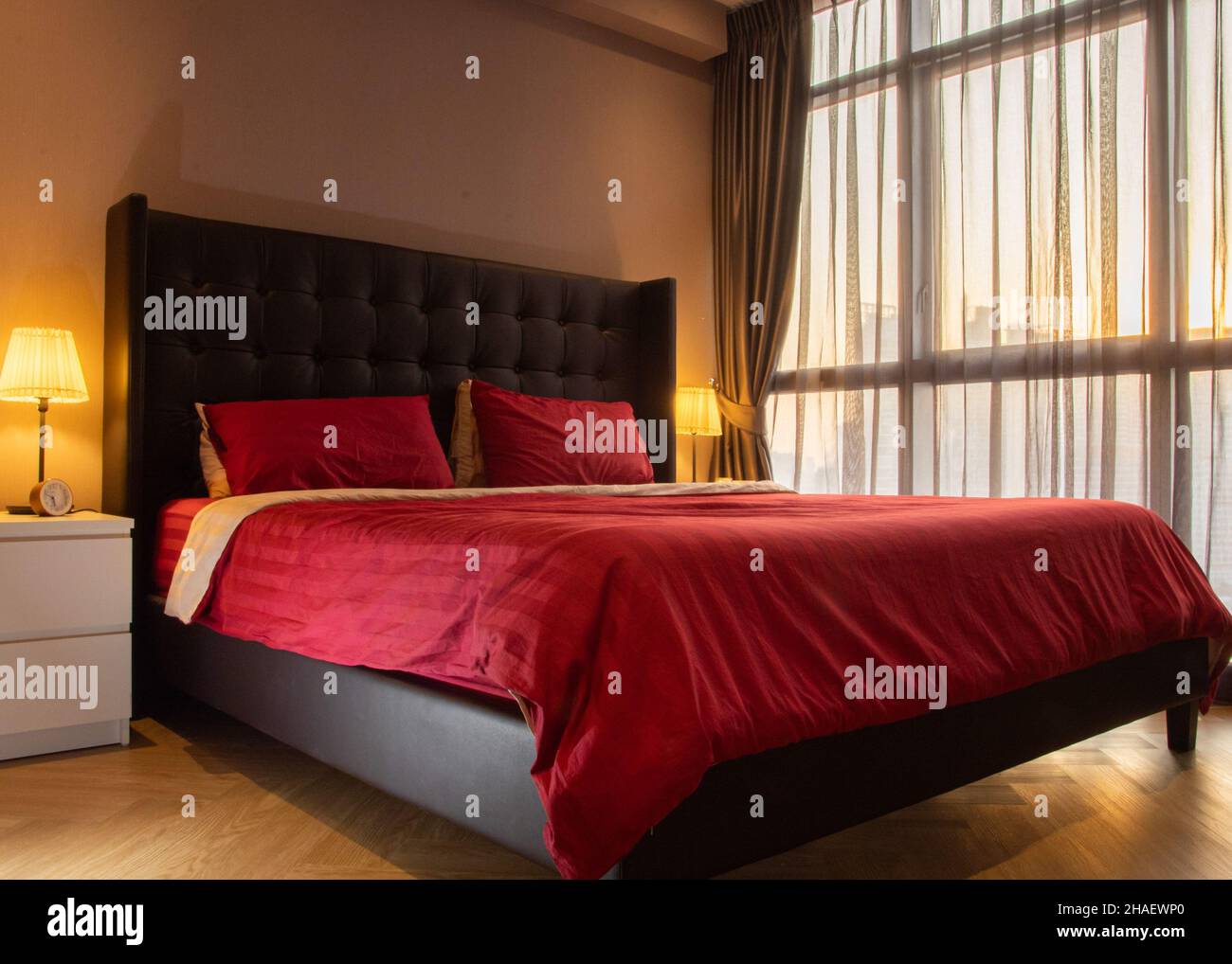 Eine Nahaufnahme eines schönen Schlafzimmers mit schöner roter Abdeckung auf dem Bett Stockfoto