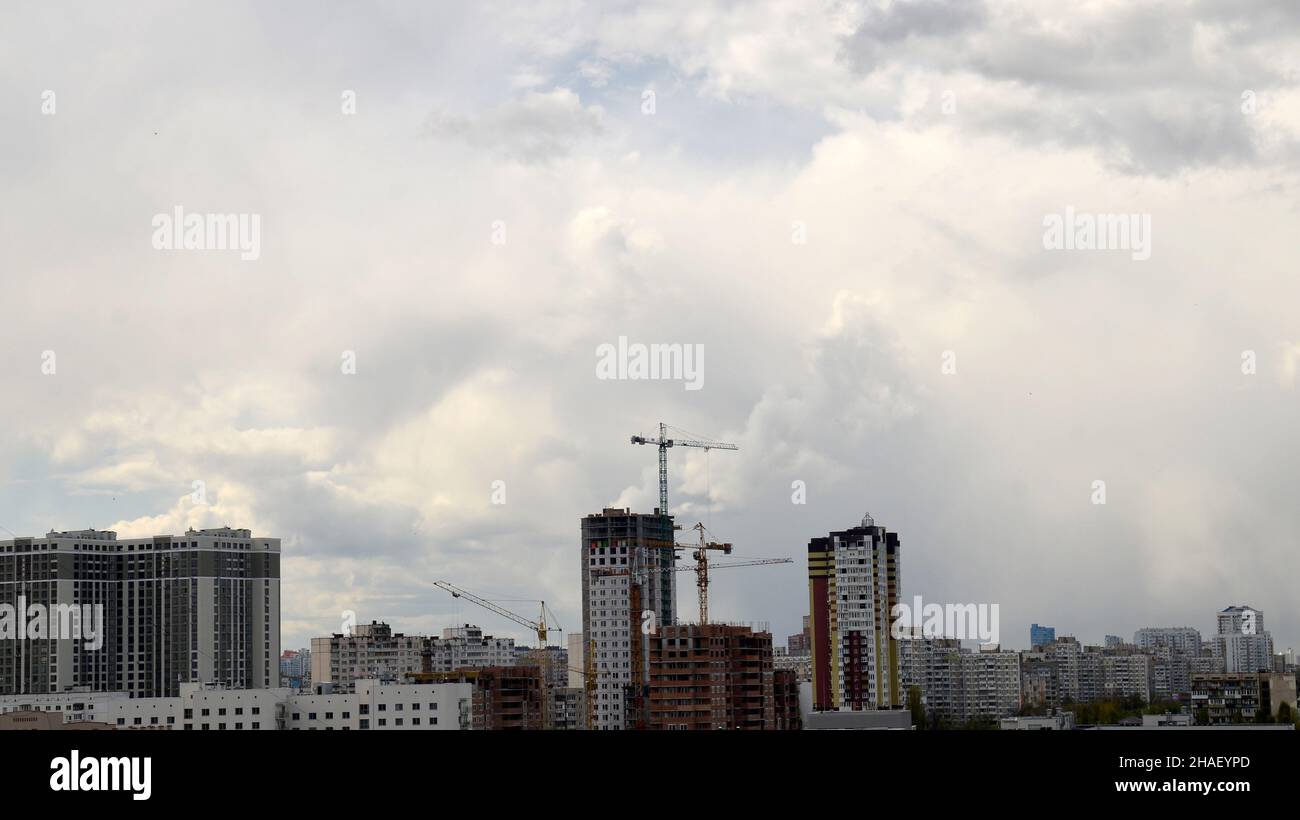 Bauprozess unter bewölktem Sommerhimmel, Kräne und neue moderne Gebäude im Hintergrund Stockfoto