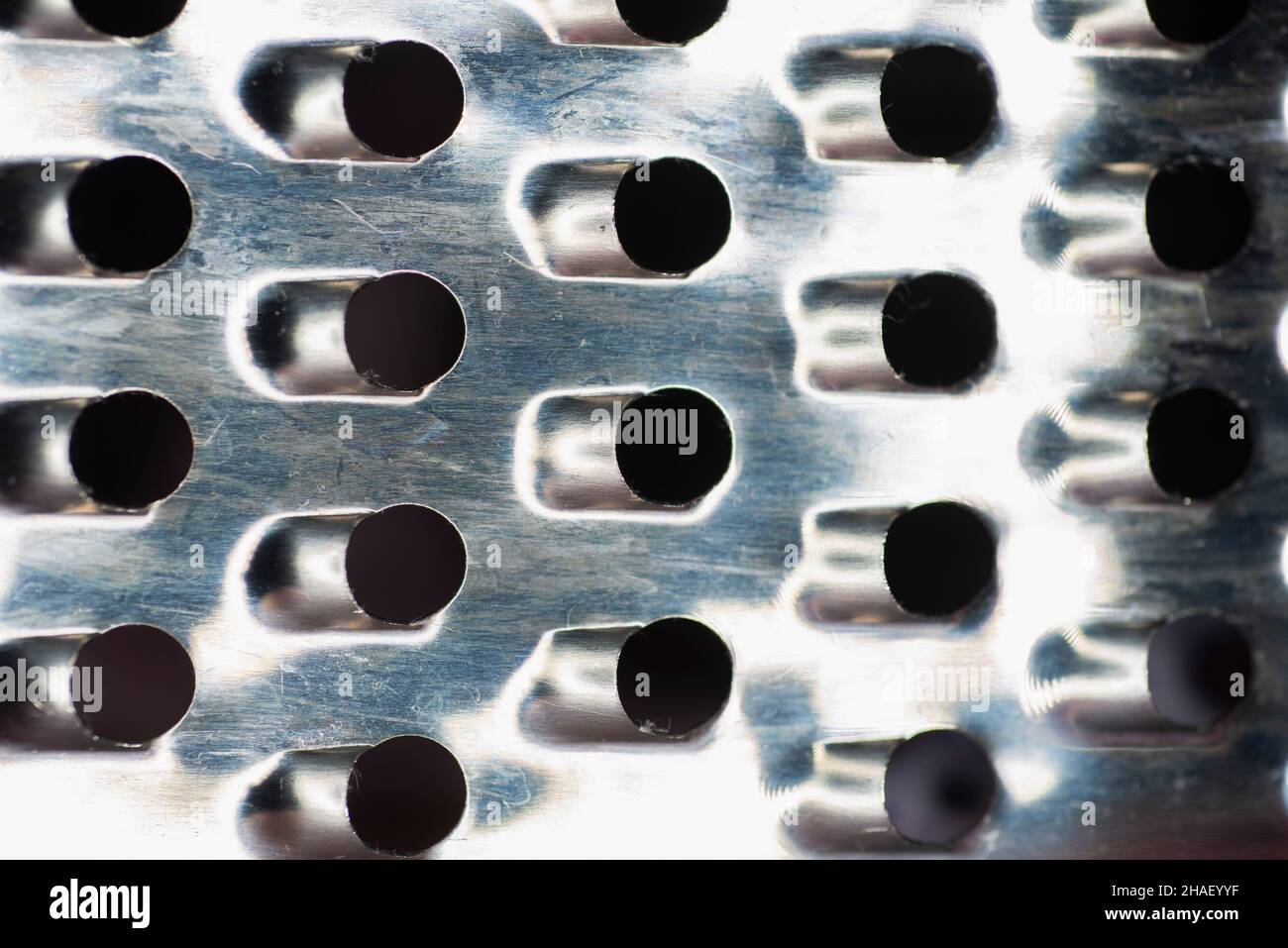 Hintergrund.: Strukturiertes, graues, scharfes Metalleisengitter, Gitter oder Edelstahlgitter. Küchenreibe aus Metall zum Kochen von Käse oder Obst oder Gemüse Stockfoto