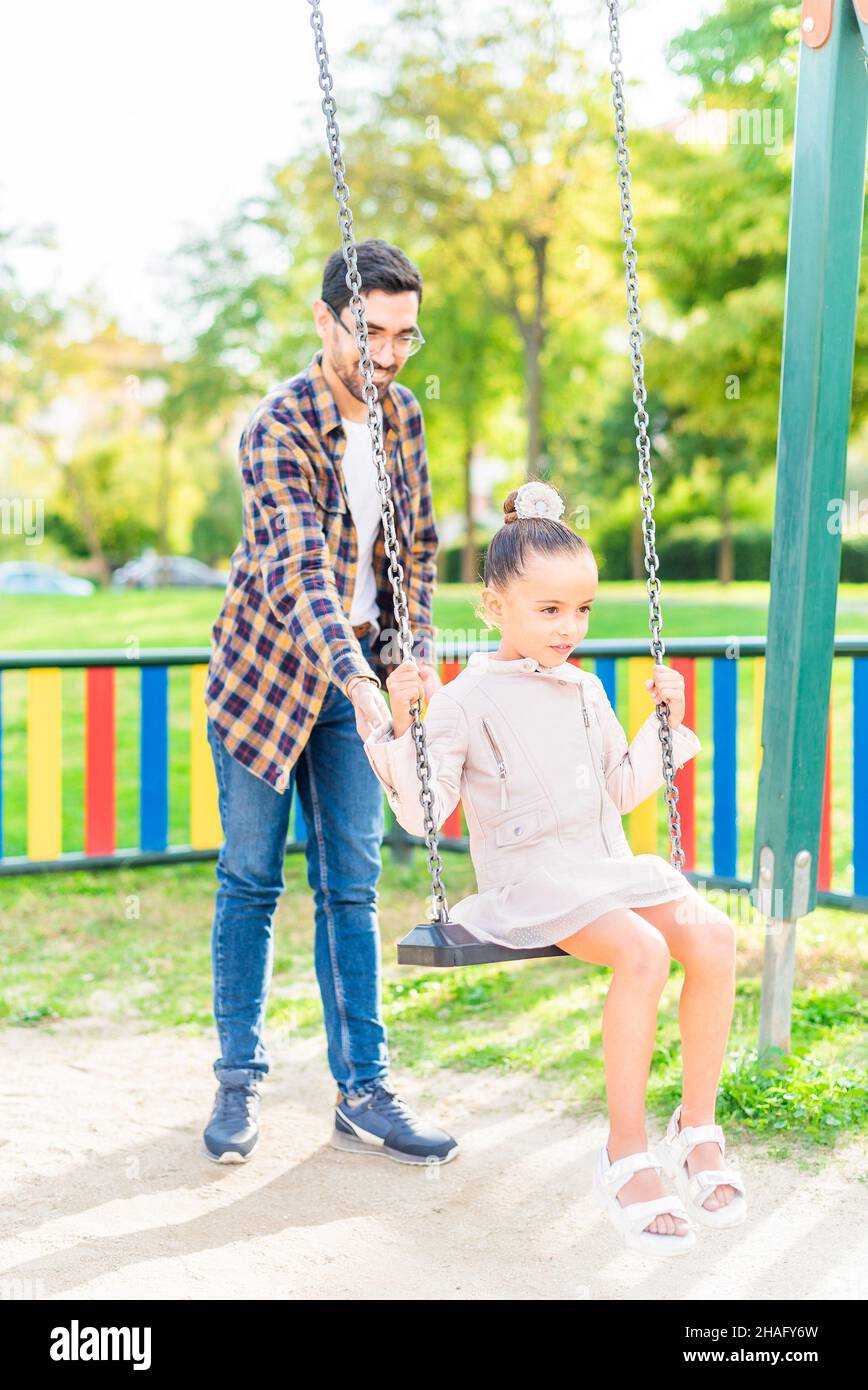 Ein Mann, der mit seiner Adoptivtochter auf der Schaukel spielt Stockfoto