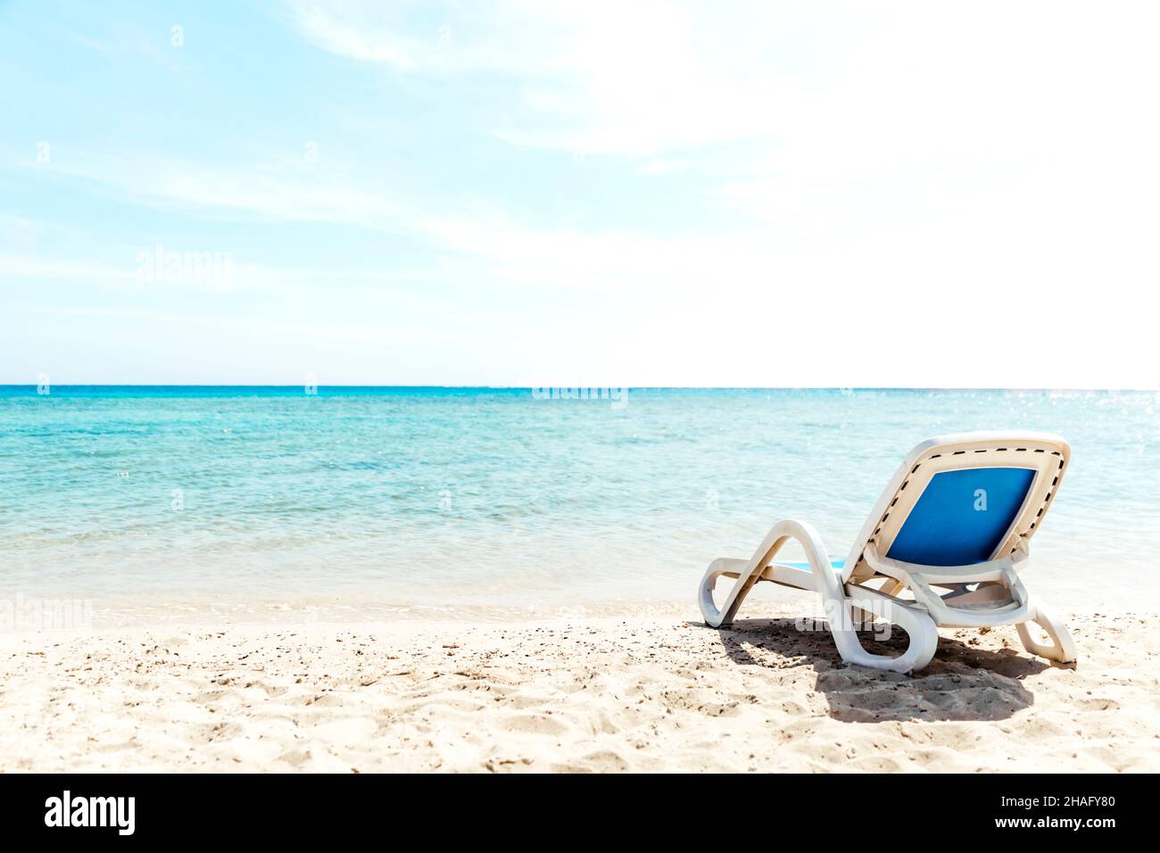 Eine einone, weiß blaue Sonnenliege steht direkt am Wasser an der Küste. Das Konzept eines Strandurlaubs am Meer oder Meer. Privater Strand des Hotels. Ruhige, ruhige Meerseite. Hochwertige Fotos Stockfoto