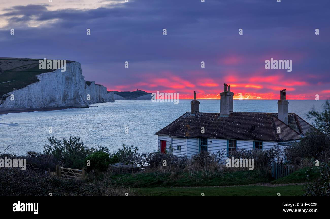 Dezember: Rote Morgendämmerung in den Küstenschutzhütten, Cuckmere Haven, Ost-Sussex, Südostengland Stockfoto
