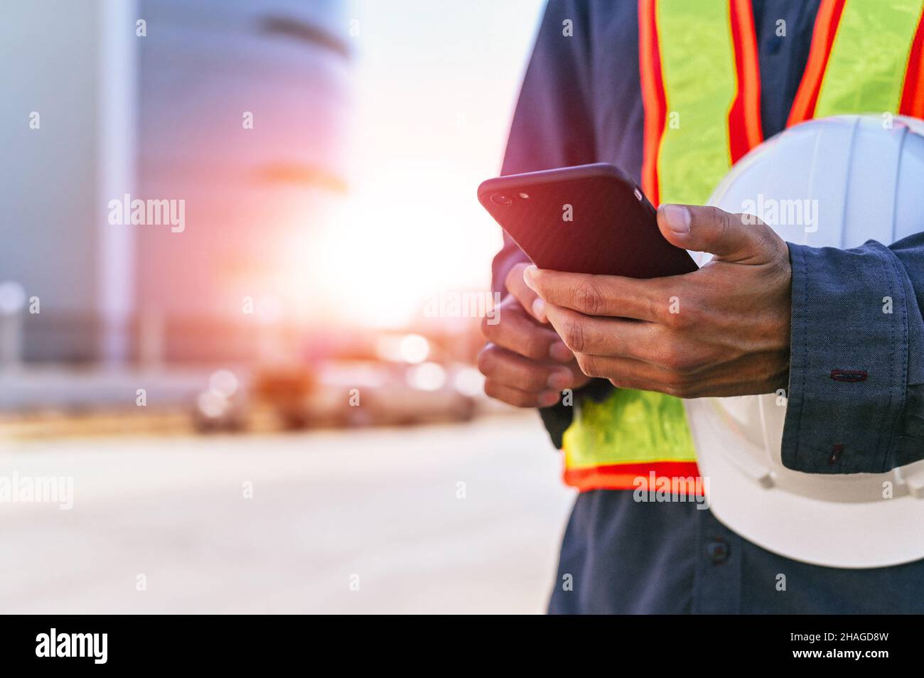 Techniker, der den Helm hält und den Arbeitsdatenbericht per Telefon sendet Stockfoto