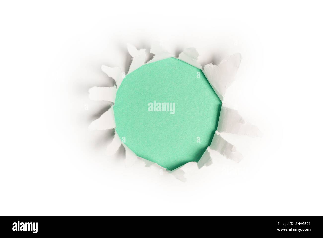 Ein Loch in einem weißen Papier auf einem grünen Hintergrund, Platz kopieren. Stockfoto