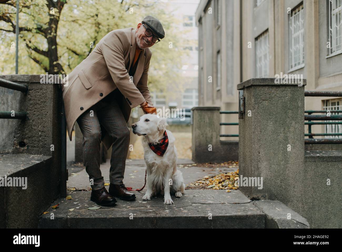 Glücklicher älterer Mann, der während eines Hundespaziergangs im Freien in der Stadt die Kamera anschaut. Stockfoto