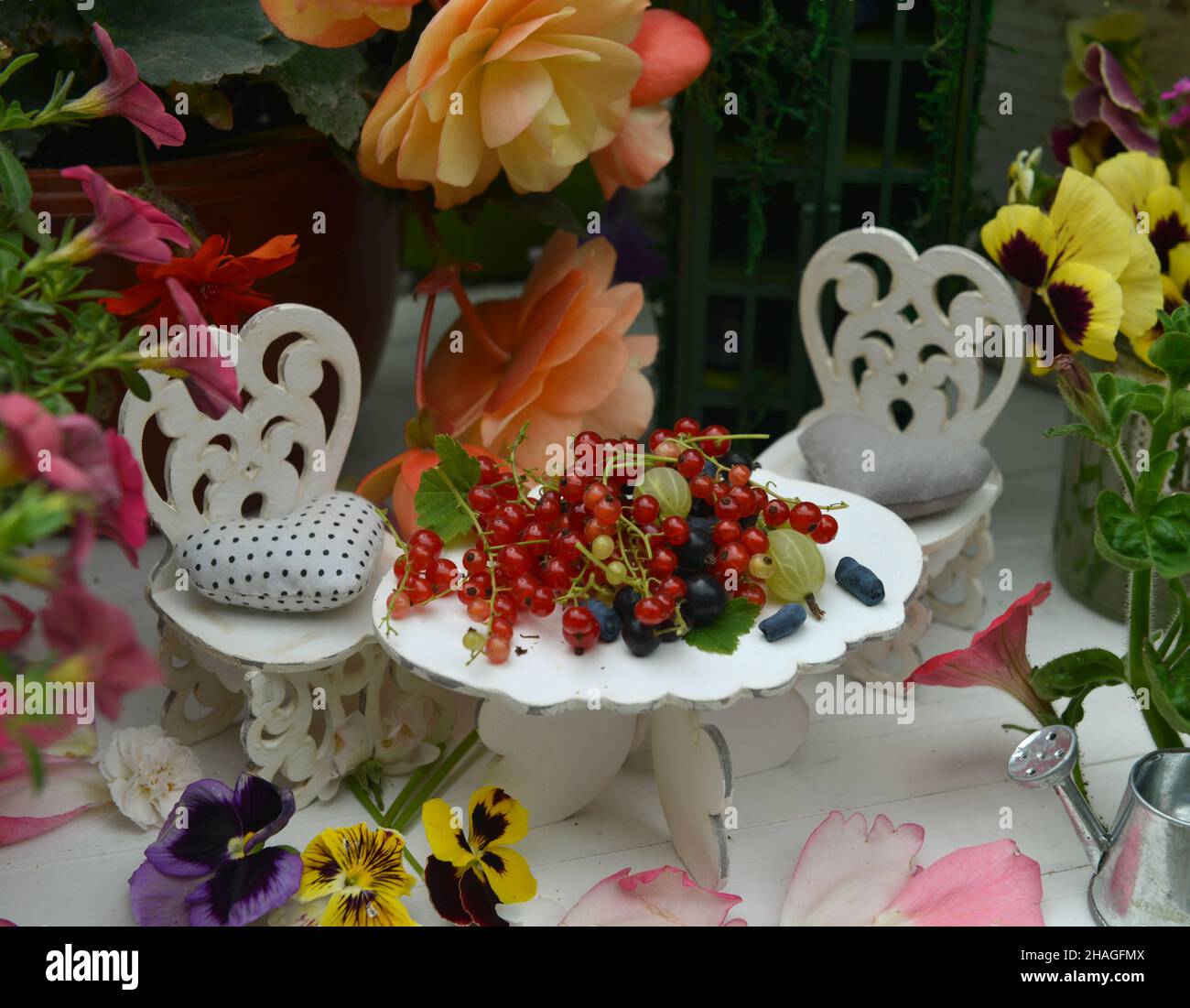 Winzig entzückender Tisch und Stühle für eine Teeparty mit Blumen und Beeren. Feen im Garten. Schöne Fabel Stillleben für Grußkarten, Hochzeit oder Stockfoto