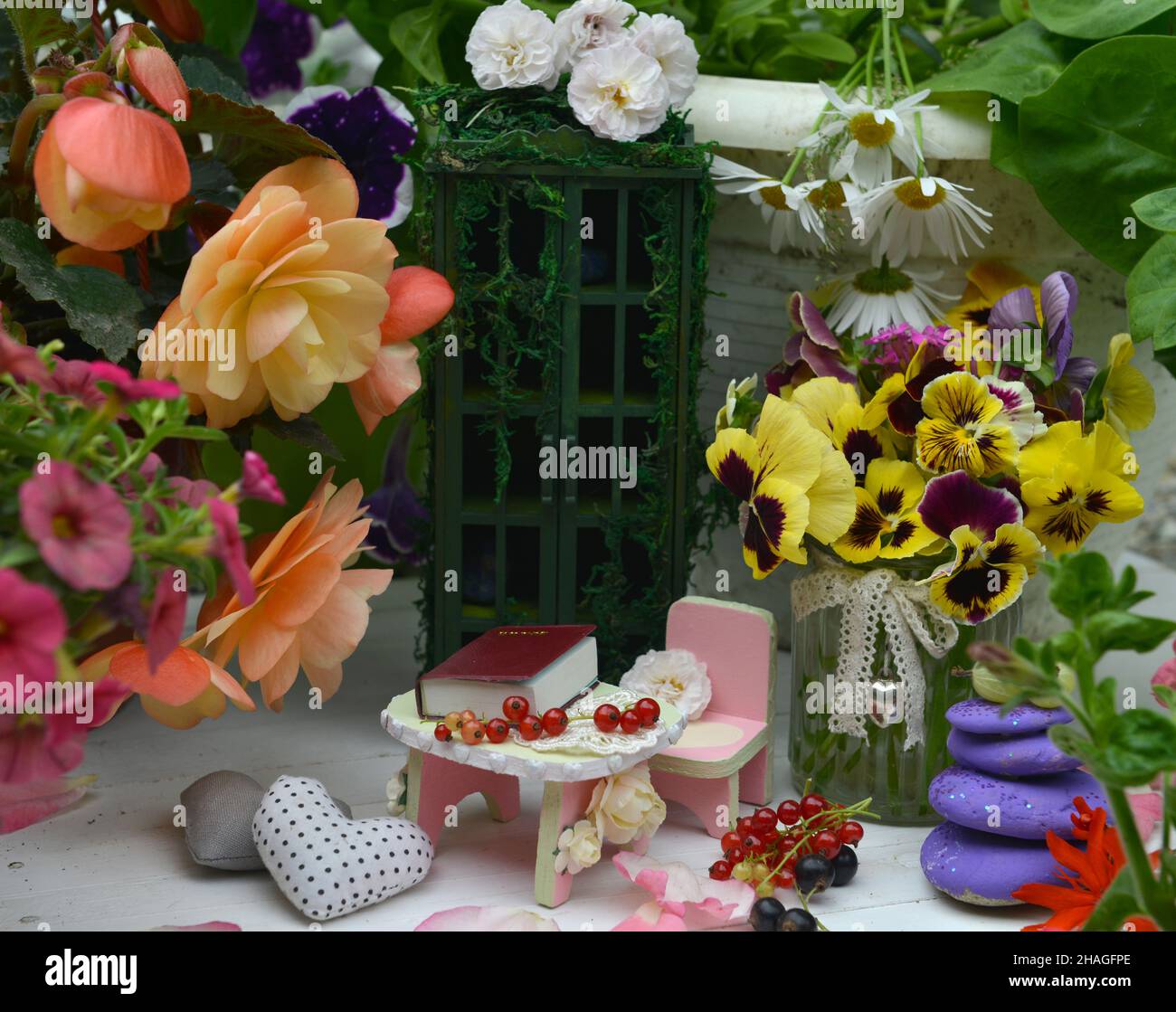 Schöne Blumen, kleiner Stuhl und Tisch mit Buch und Beeren. Feen im Garten. Schöne Fabel Stillleben für Grußkarten, Hochzeit oder Geburtswohne Stockfoto