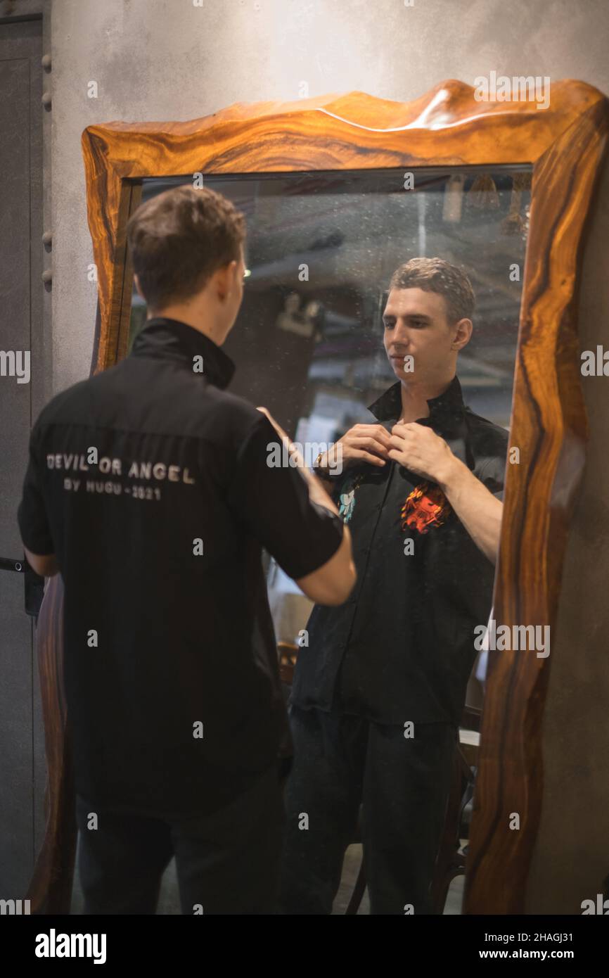 Porträt eines jungen kaukasischen Mannes in schwarzem Polo, der im Café steht und auf den Spiegel schaut. Hochwertige Fotos Stockfoto