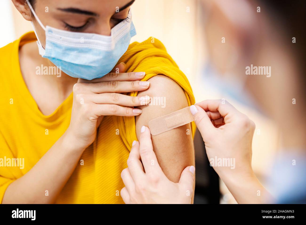 Globale Impfungen und Gesundheitsfürsorge. Die Nahaufnahme der Krankenschwester, die nach der Injektion einen klebrigen Verbandsputz auf den Arm des Mädchens legte, kovid 19-Impfstoff. Stockfoto