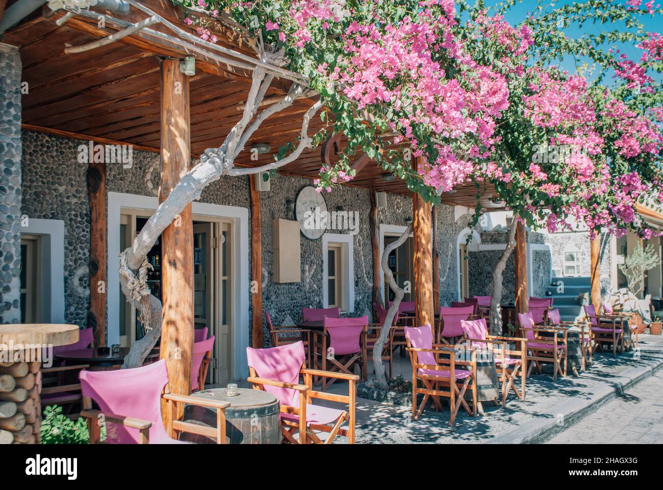 Die Veranda des Sommercafés mit rosafarbenen Sesseln ist mit rosafarbenen Blumen verschlungen Stockfoto