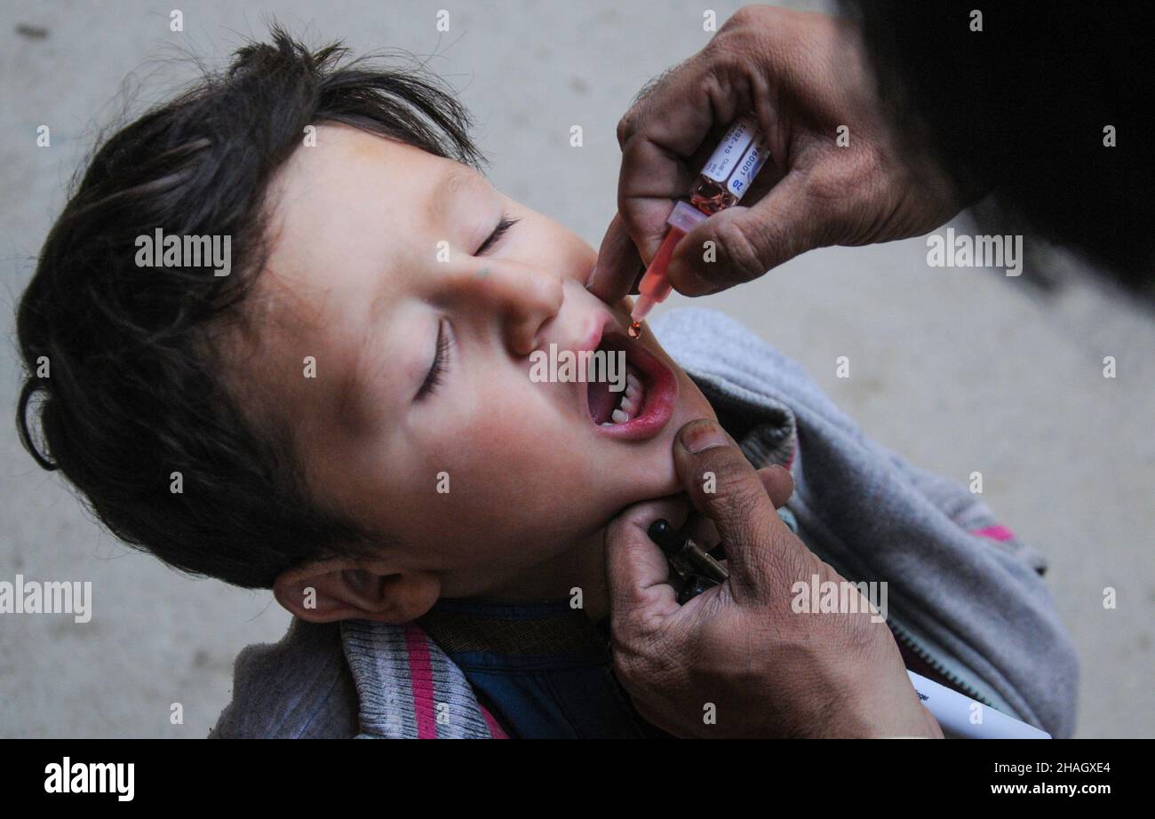 RAWALPINDI, Pakistan – 13. Dezember: Ein Gesundheitsmitarbeiter verabreicht einem Kind während einer Anti-Polio-Kampagne in Rawalpindi am 13. Dezember 2021 einen Polio-Impfstoff Stockfoto
