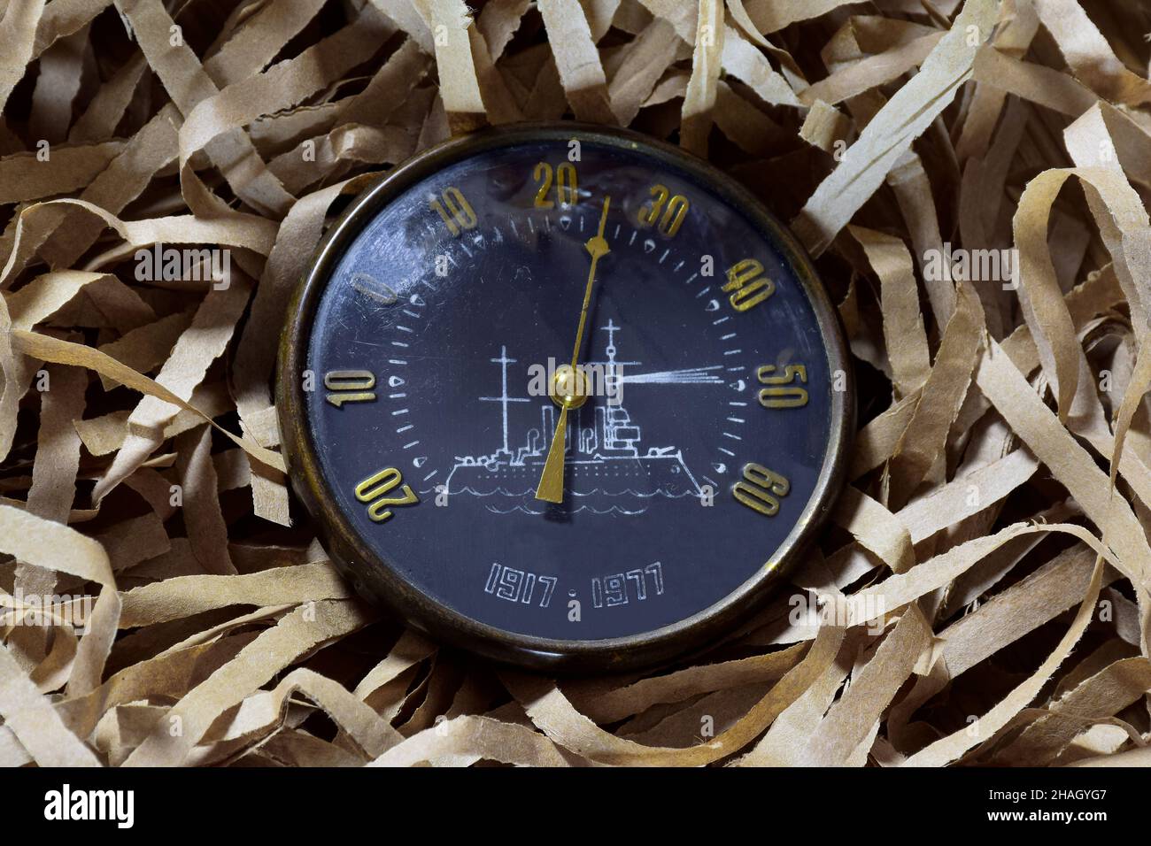 Ein altes Vintage-Straßenthermometer in kreisförmiger Form mit analogem, kreisförmigem Zifferblatt ruht auf verschlungenen Papierstreifen Stockfoto