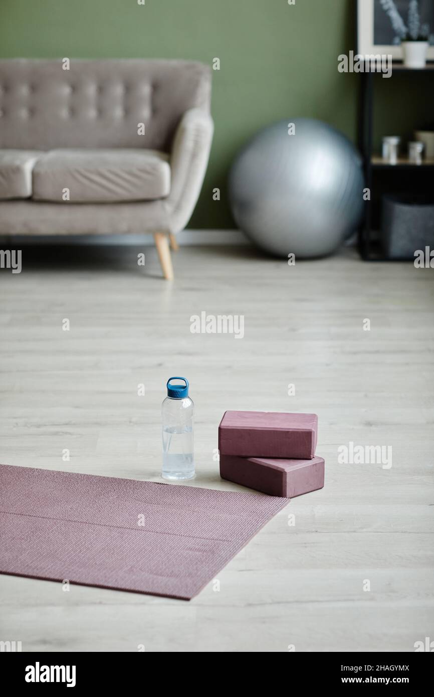 Vertikales Hintergrundbild des Wohnraums mit Yogamatte auf dem Boden, Indoor-Workout-Konzept, Kopierraum Stockfoto