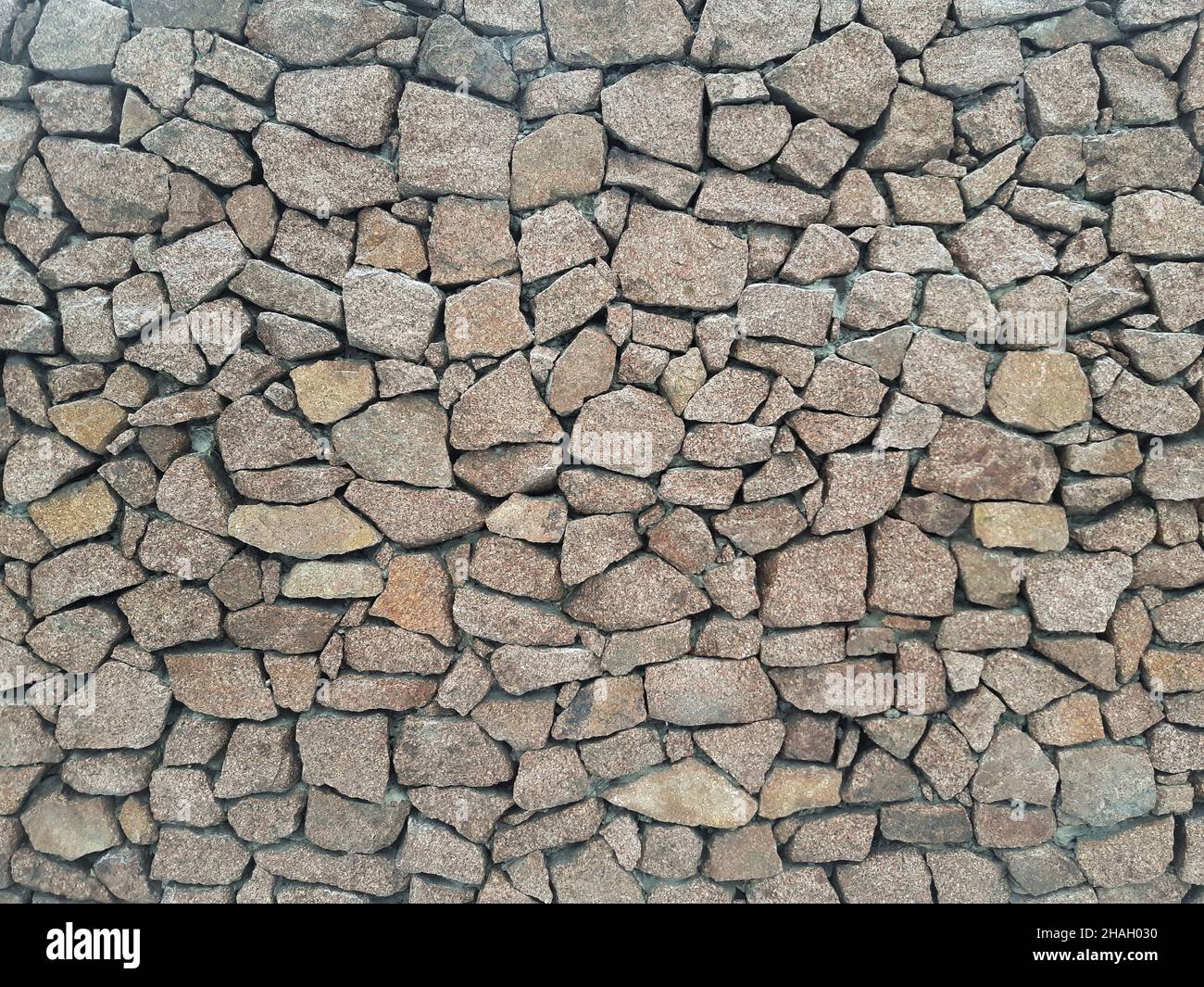 Steinwand aus grauem Granit, verstärkt mit Zement für den gesamten Rahmen von Steinen verschiedener Größen und Formen Stockfoto