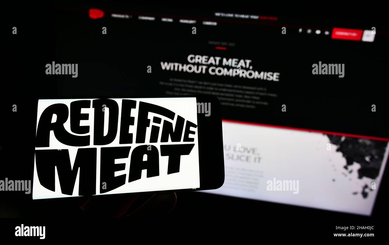 Person, die Mobiltelefon mit dem Logo des israelischen Kulturfleischunternehmens Redefine Meat Ltd. Auf dem Bildschirm vor der Webseite hält. Konzentrieren Sie sich auf die Telefonanzeige. Stockfoto