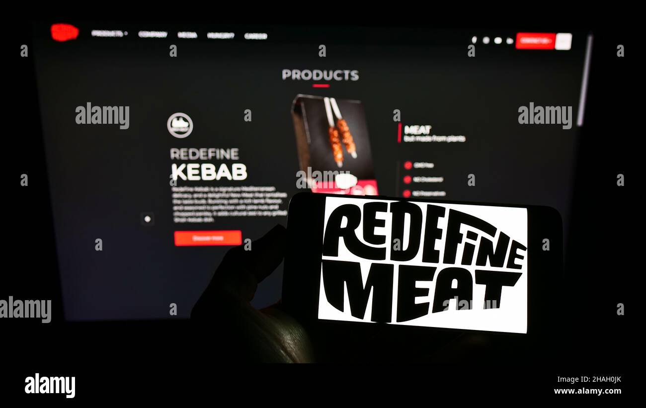 Person, die Cellpohone mit dem Logo des israelischen Kulturfleischunternehmens Redefine Meat Ltd. Auf dem Bildschirm vor der Webseite hält. Konzentrieren Sie sich auf die Telefonanzeige. Stockfoto