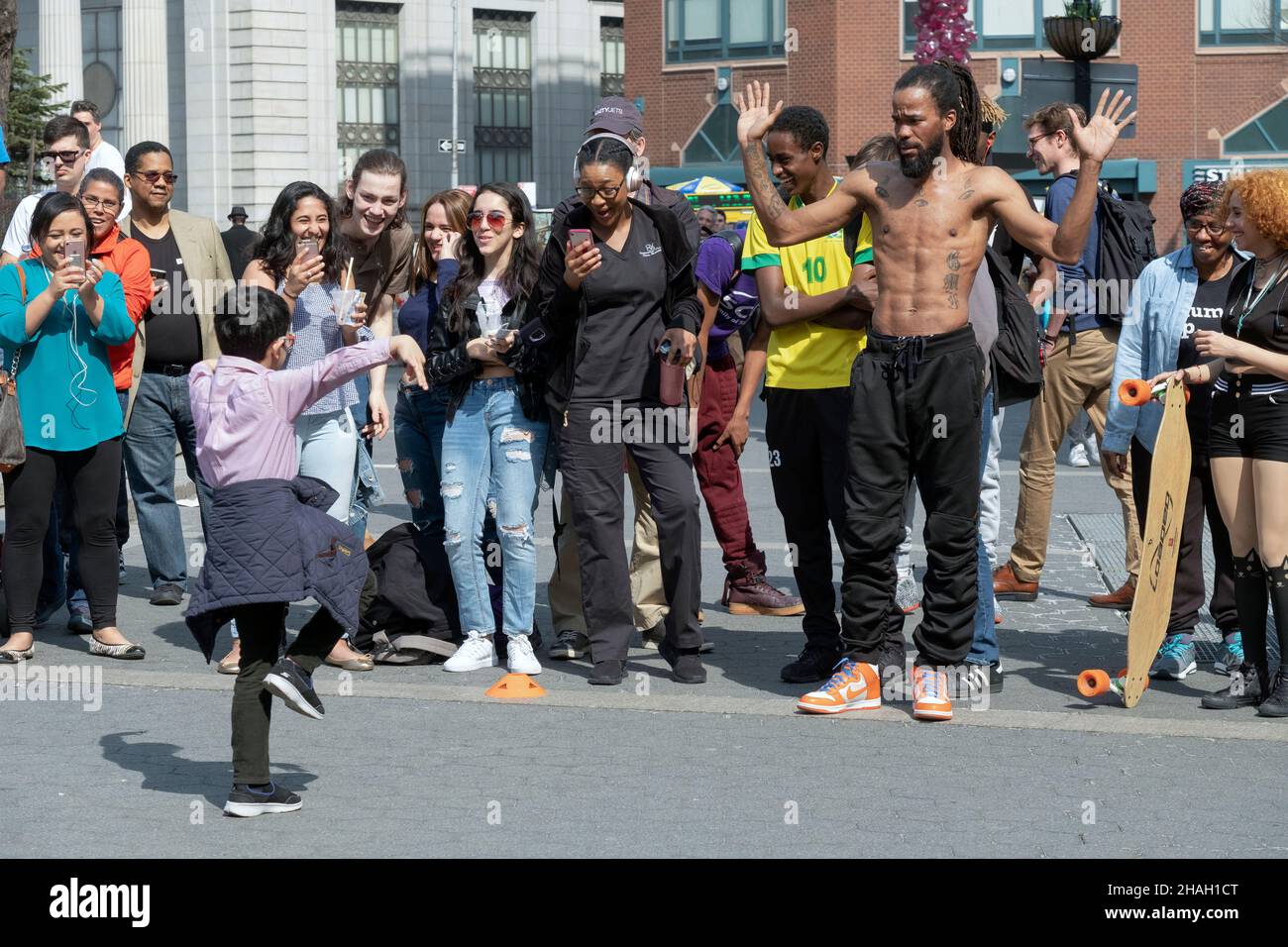 Ein junger Bursche führt zur Freude des Publikums einen professionellen Busskertänzer nach oben. Im Union Square Park, Lower manhattan, New York City. Stockfoto