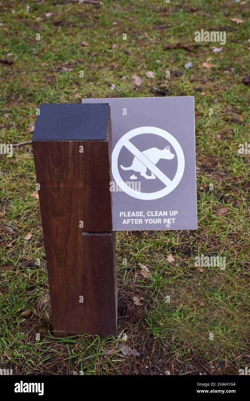 Ein Beitrag im Park mit einem Schild, das Hundebesitzer dazu auffordert, Exkremente nach ihren Haustieren zu säubern Stockfoto