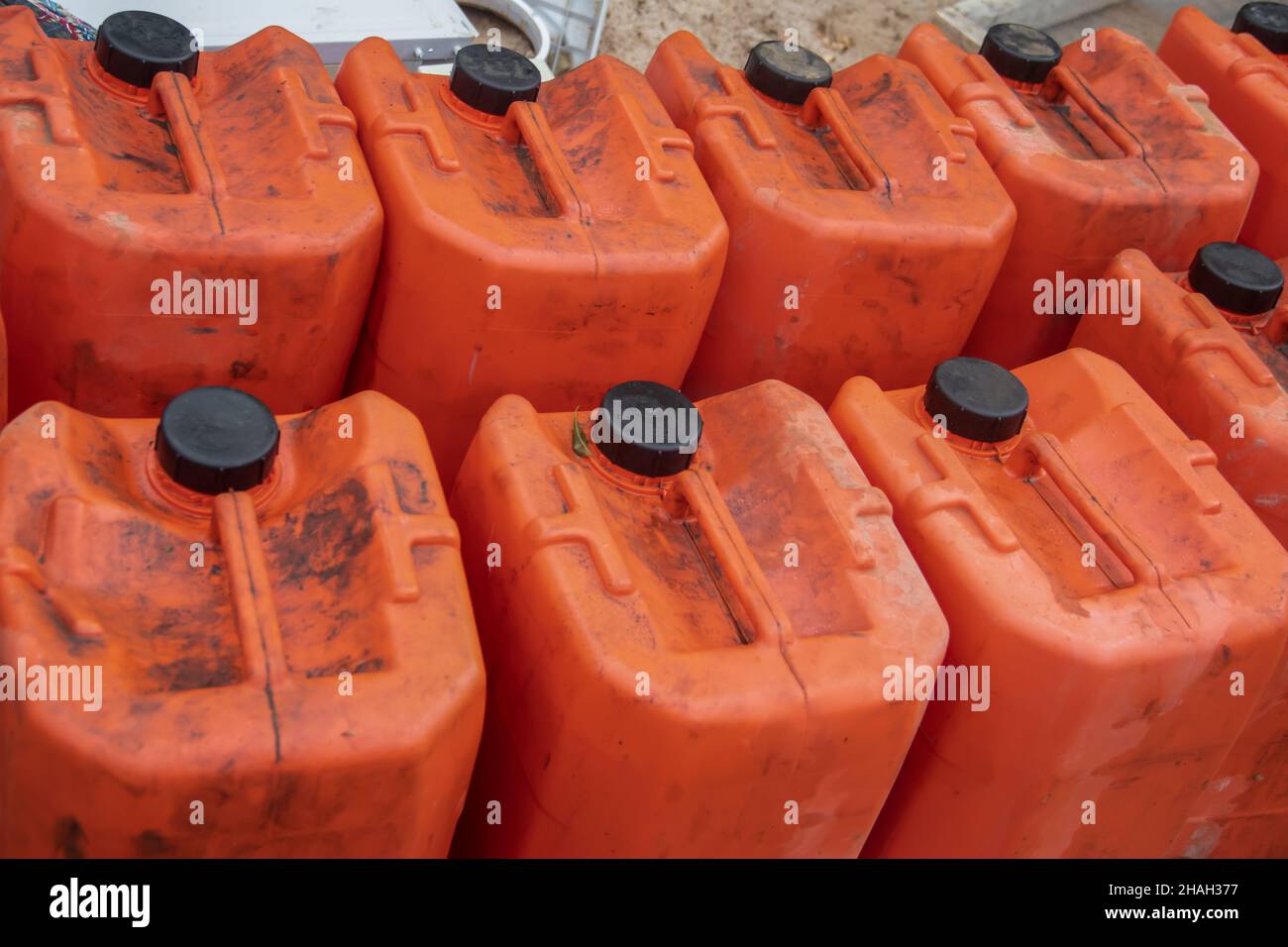 Alte gebrauchte orangefarbene Kanister in der mechanischen Werkstatt, voll mit altem Altöl, bereit zum Recycling Stockfoto