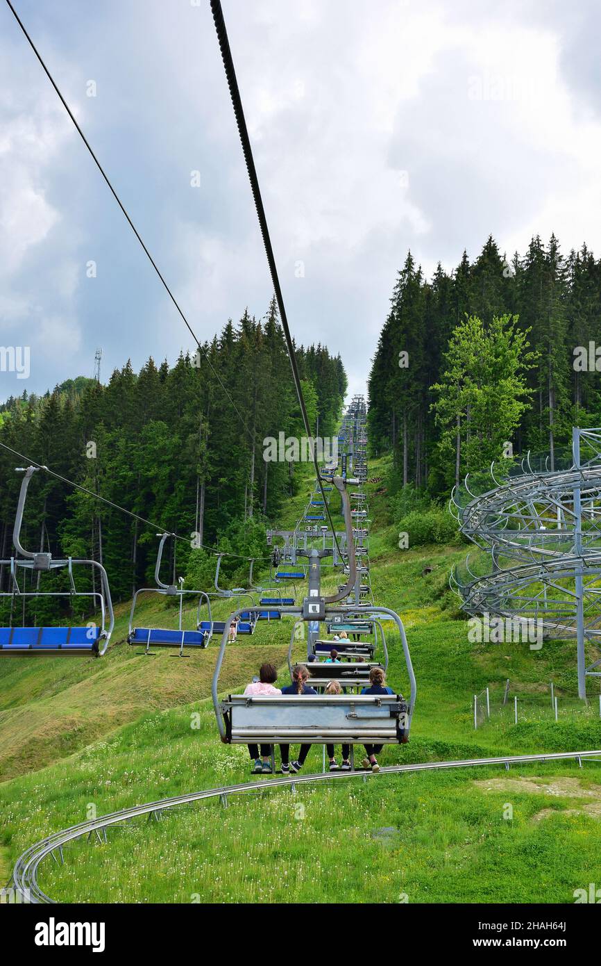 Ein Lift mit vielen Bänken bringt die Menschen auf den mit Bäumen bedeckten Berg. Foto im Sommer, viele Bänke sind leer Stockfoto