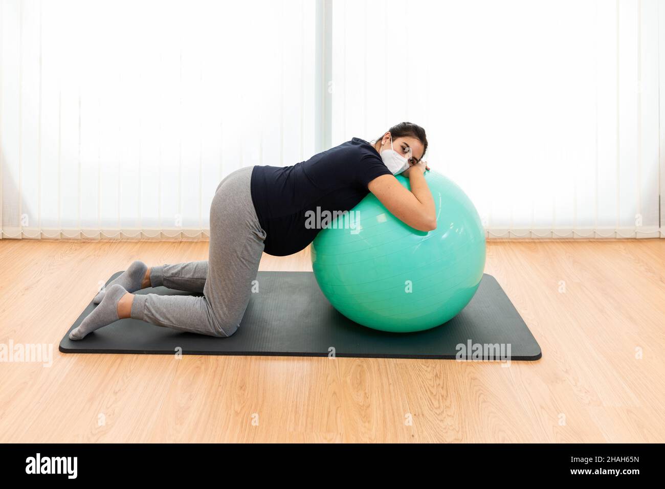 Eine Schwangerin macht Atemübungen und ruht sich auf einem Fitnessball aus Stockfoto