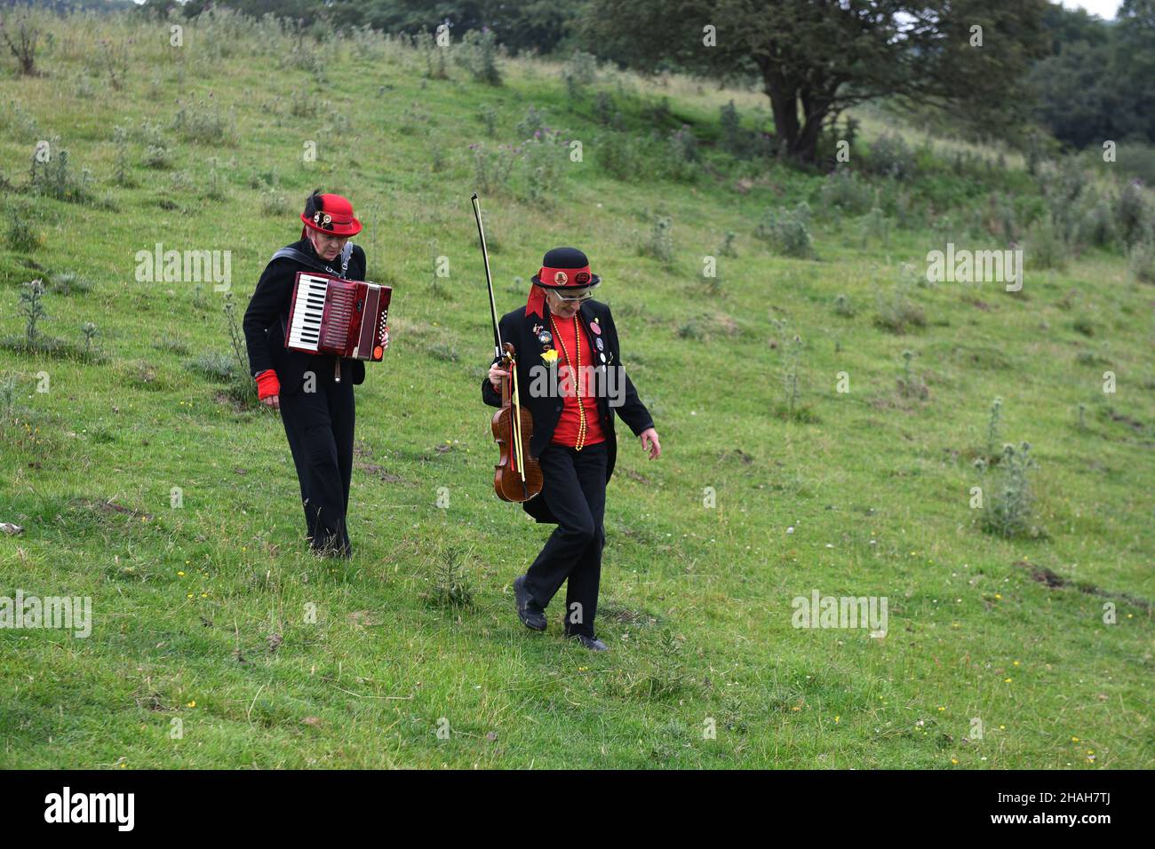 Musiker der traditionellen Tanzgruppe Ironmen & Severn Gilders gehen über ein Feld Stockfoto