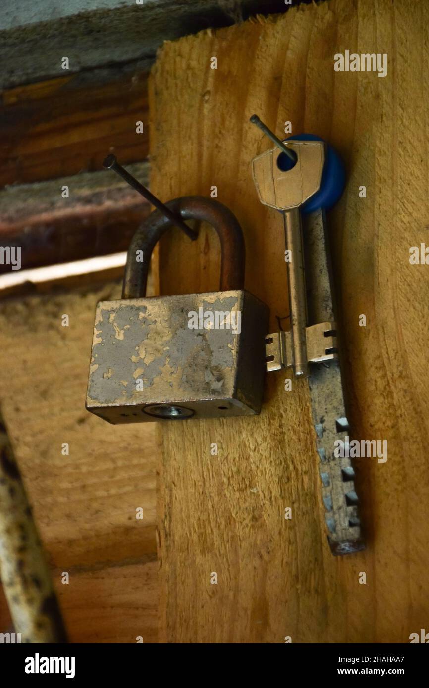 An der Holzwand befinden sich eine Reihe verschiedener Schlüssel und ein Vorhängeschloss. Stockfoto