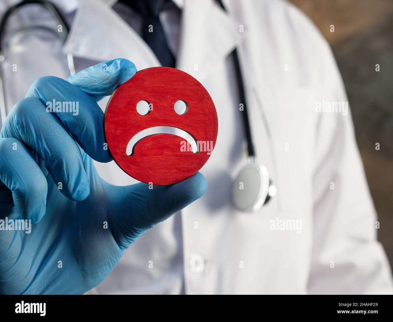 Negative Patientenerfahrung oder negatives Ergebnis. Der Arzt hält ein unglückliches Smiley. Stockfoto