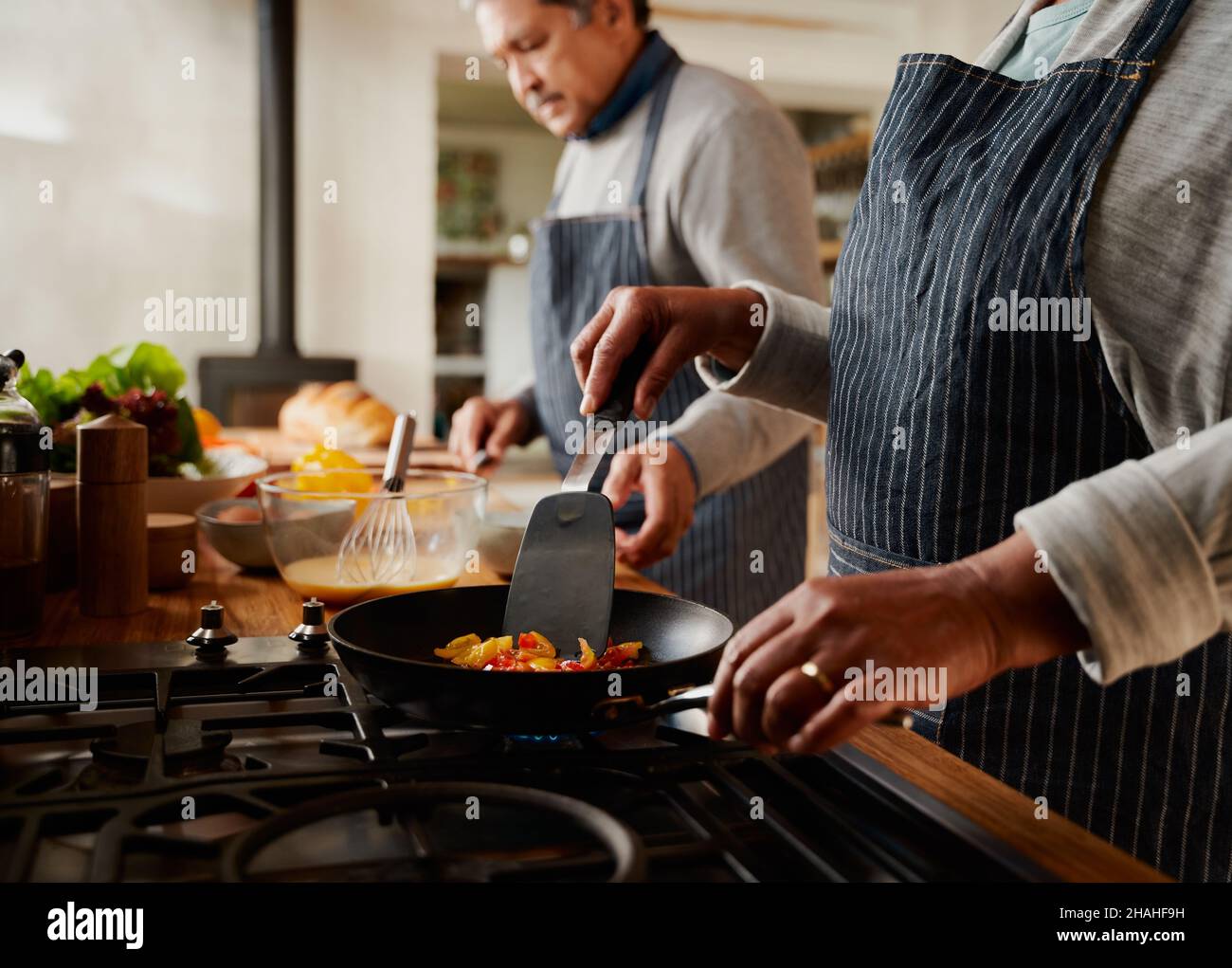 Fröhliches multikulturelles älteres Paar, das in einer modernen Küche gemeinsam gesundes Frühstück kocht. Stockfoto