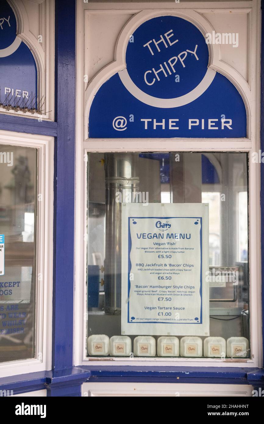 Ein veganes Menü außerhalb eines Fish-n-Chip-Shops, das auf die Nachfrage nach veganem und vegetarischem Essen auf dem Eastbourne Pier in East Sussex, Großbritannien, angepickt ist. Stockfoto