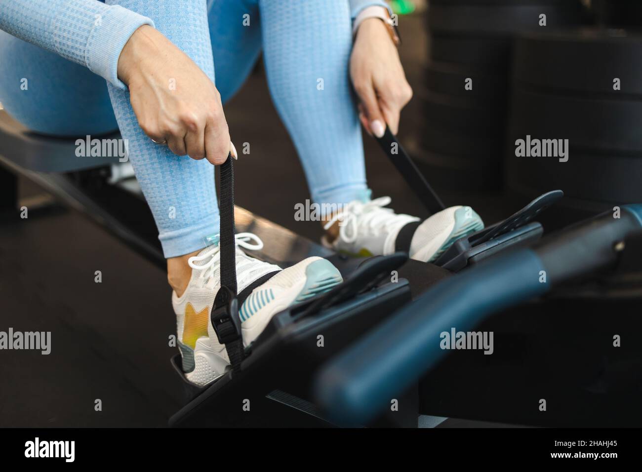 Frau bereitet sich auf Ruderübungen vor. Mädchen sitzt auf einem Rudergerät Stockfoto
