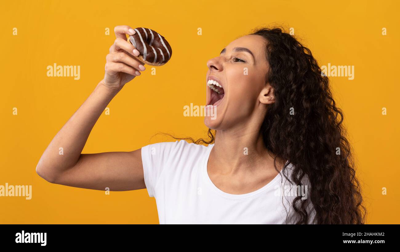 Happy Latin Lady Holding Donut Beißkuchen Im Studio Stockfoto