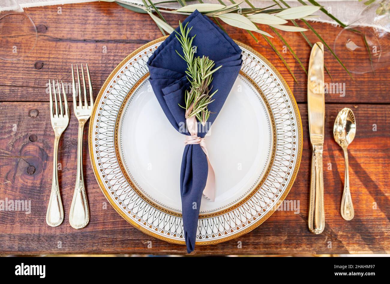 Wunderschöner Teller und Besteck mit Dekoration auf einem Holztisch für Abendessen oder Hochzeitsempfänge im Freien. Stockfoto