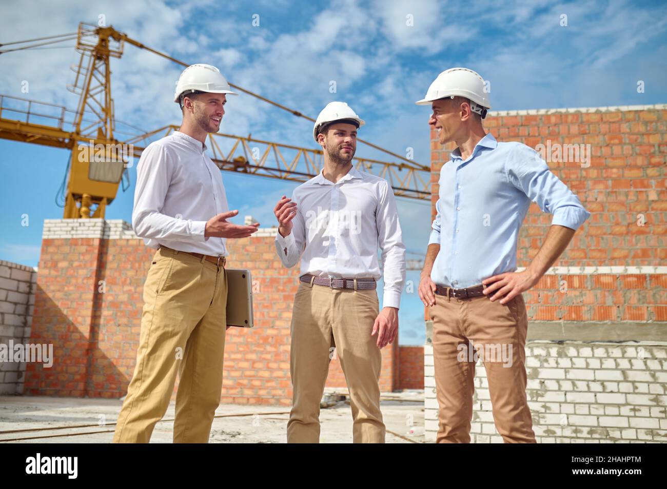 Drei Männer kommunizieren auf der Baustelle Stockfoto