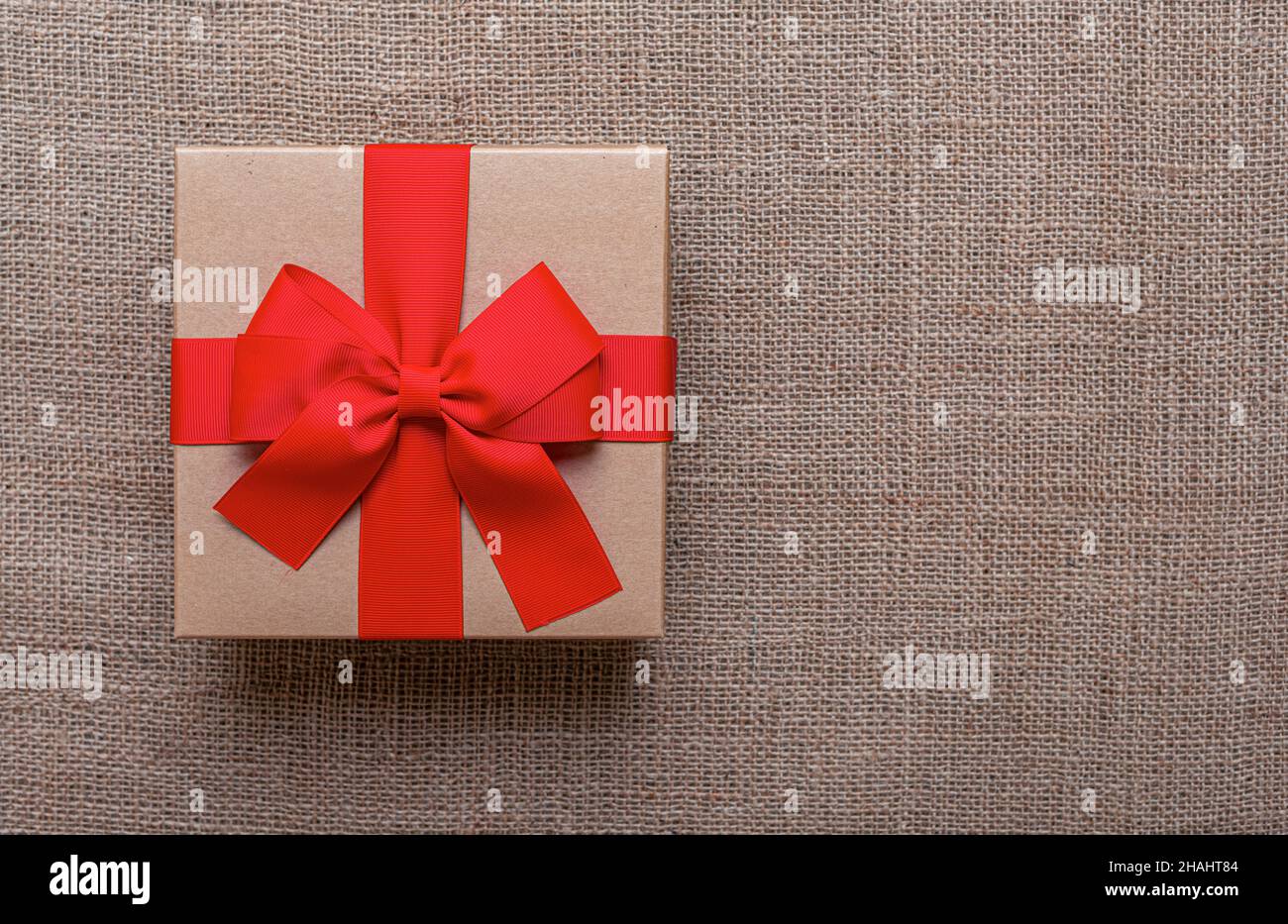 Die Geschenkbox liegt auf einem Sackleinen Hintergrund. Stockfoto