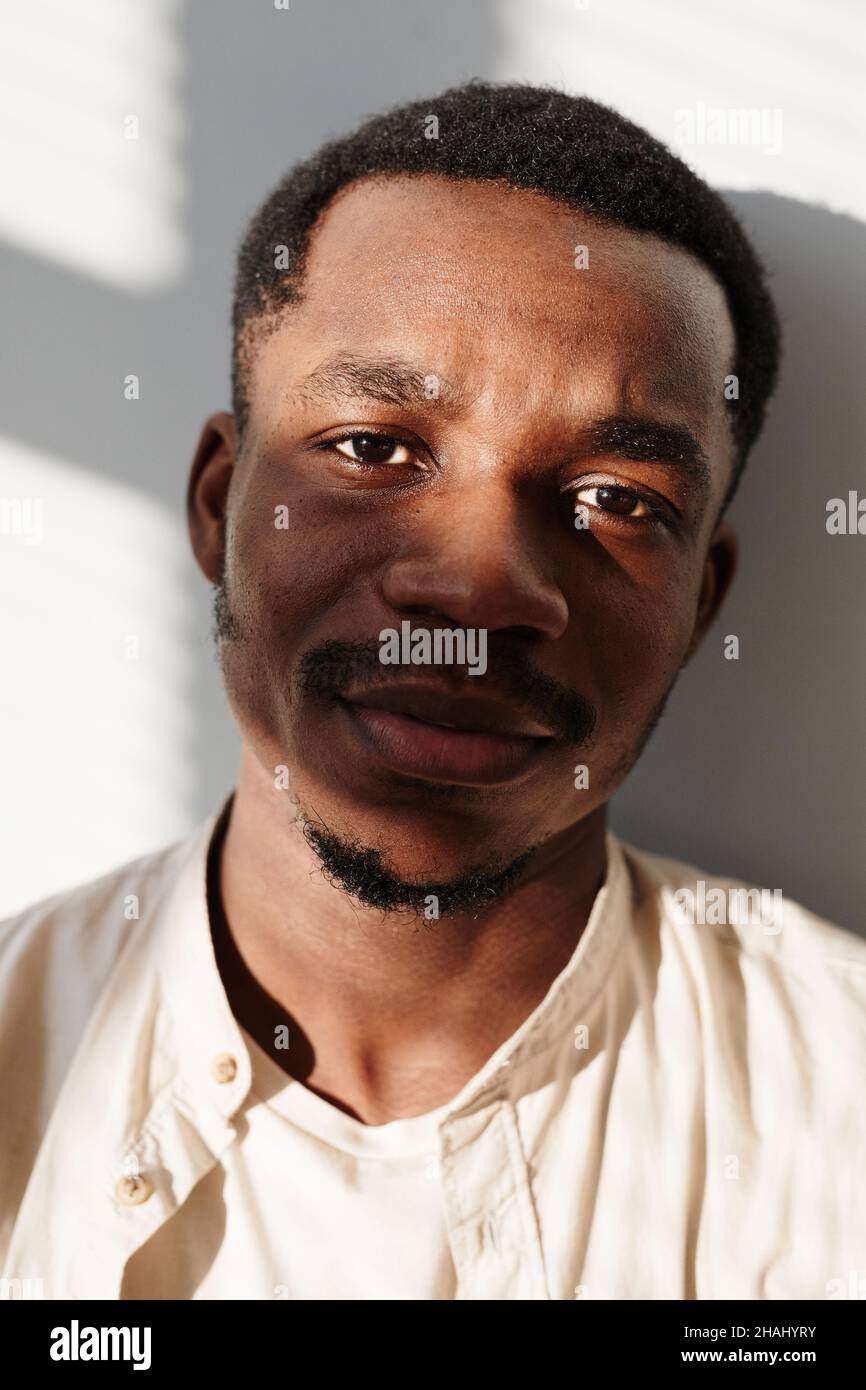 Nahaufnahme eines afrikanischen jungen Mannes im Hemd, der isoliert auf weißem Hintergrund auf die Kamera blickt Stockfoto