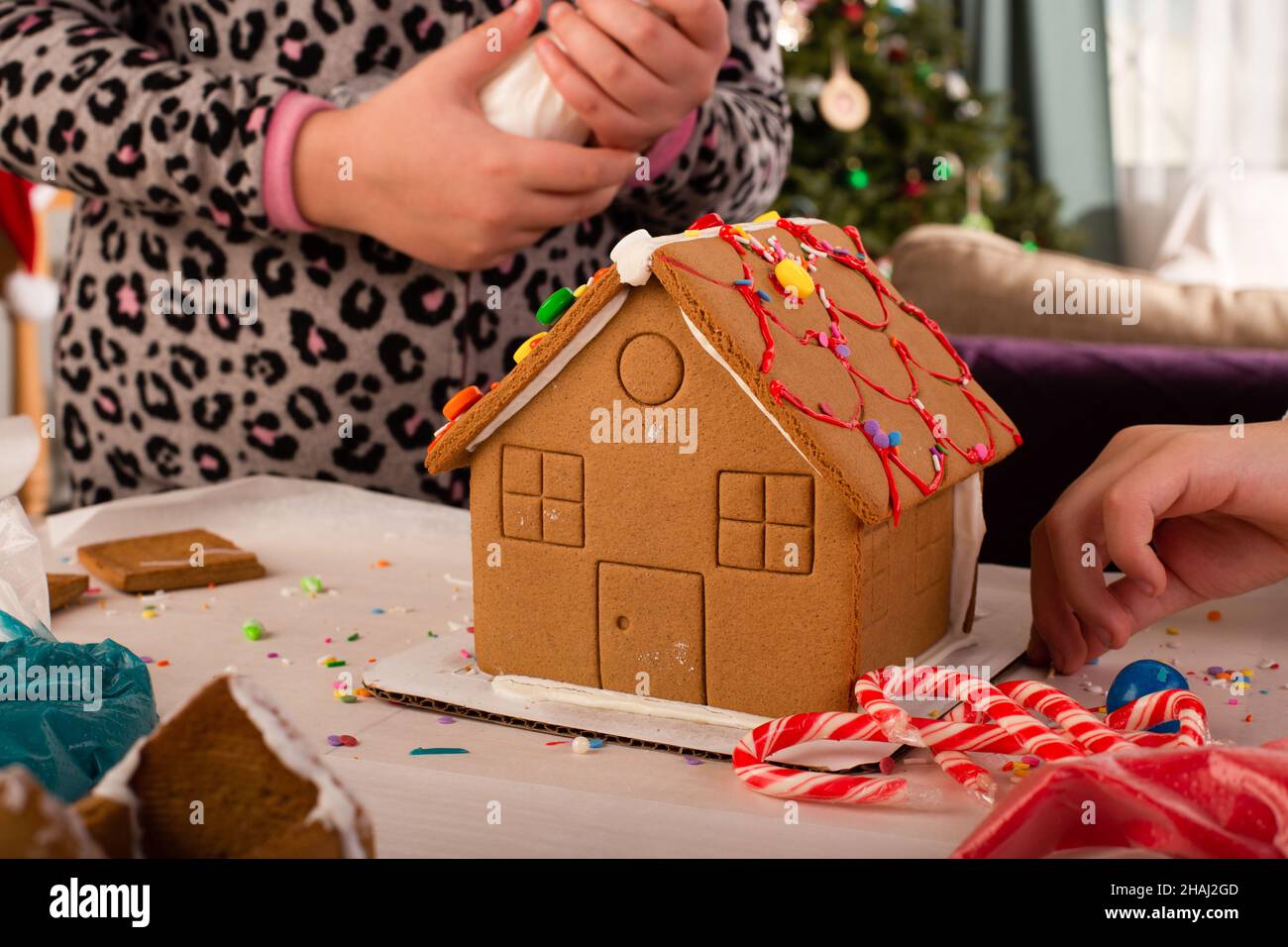 Kinder bauen und dekorieren ein Lebkuchenhaus zur Weihnachtszeit. Weihnachten Familientradition, Weihnachtshandwerk. Stockfoto