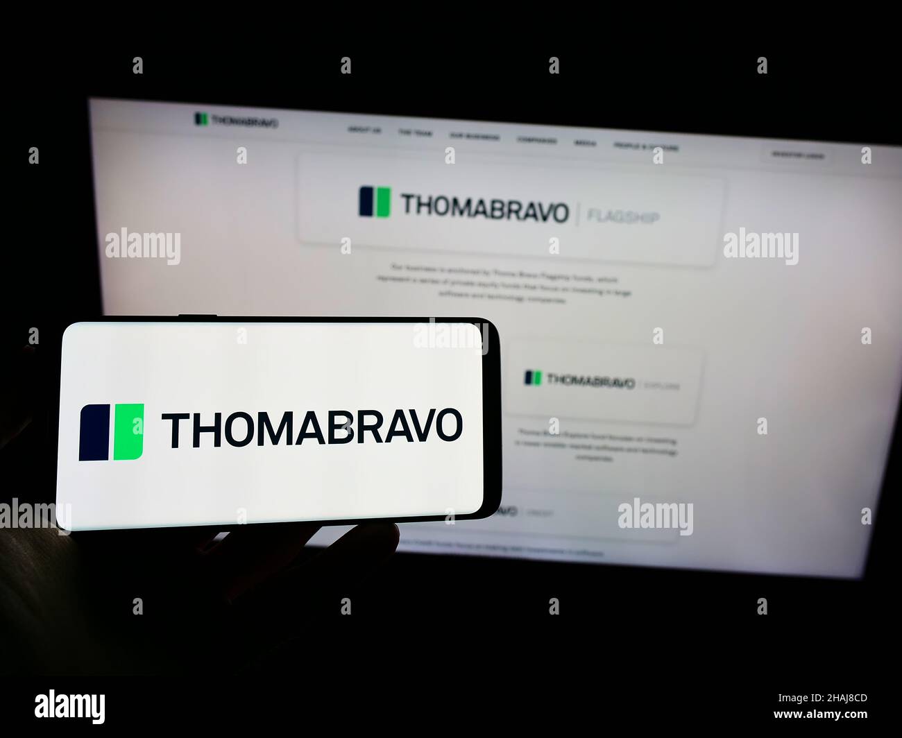 Person, die Mobiltelefon mit dem Logo der US-amerikanischen Private-Equity-Gesellschaft Thoma Bravo L.P. auf dem Bildschirm vor der Business-Webseite hält. Konzentrieren Sie sich auf die Telefonanzeige. Stockfoto