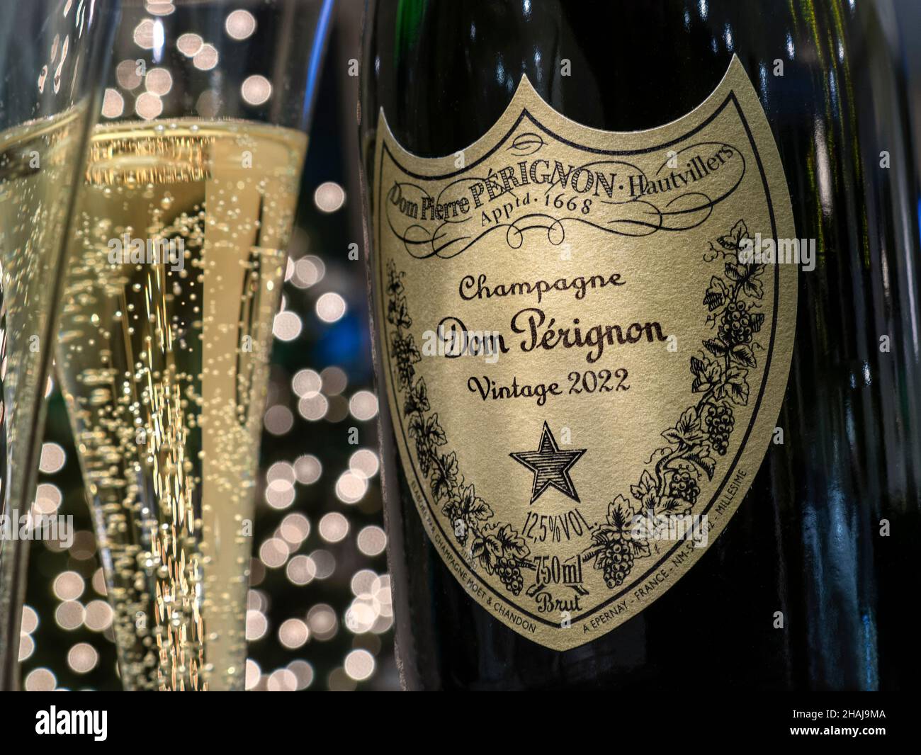 Dom Perignon 2022 Champagner-Flaschenetikett und Glas mit Blasen, Party mit funkelnden Lichtern im Hintergrund Neujahrsfeier Hotelparty Empfang Stockfoto