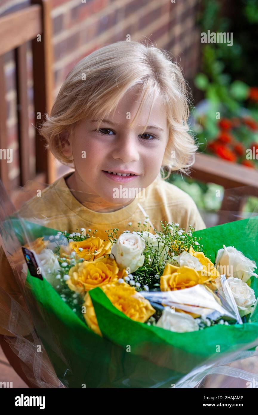 MUTTERTAG BLUMEN SOHN Junge 5-7 Jahre Blumenstrauß Präsentation für besonderen Tag Geburtstag Muttertag Feier Stockfoto
