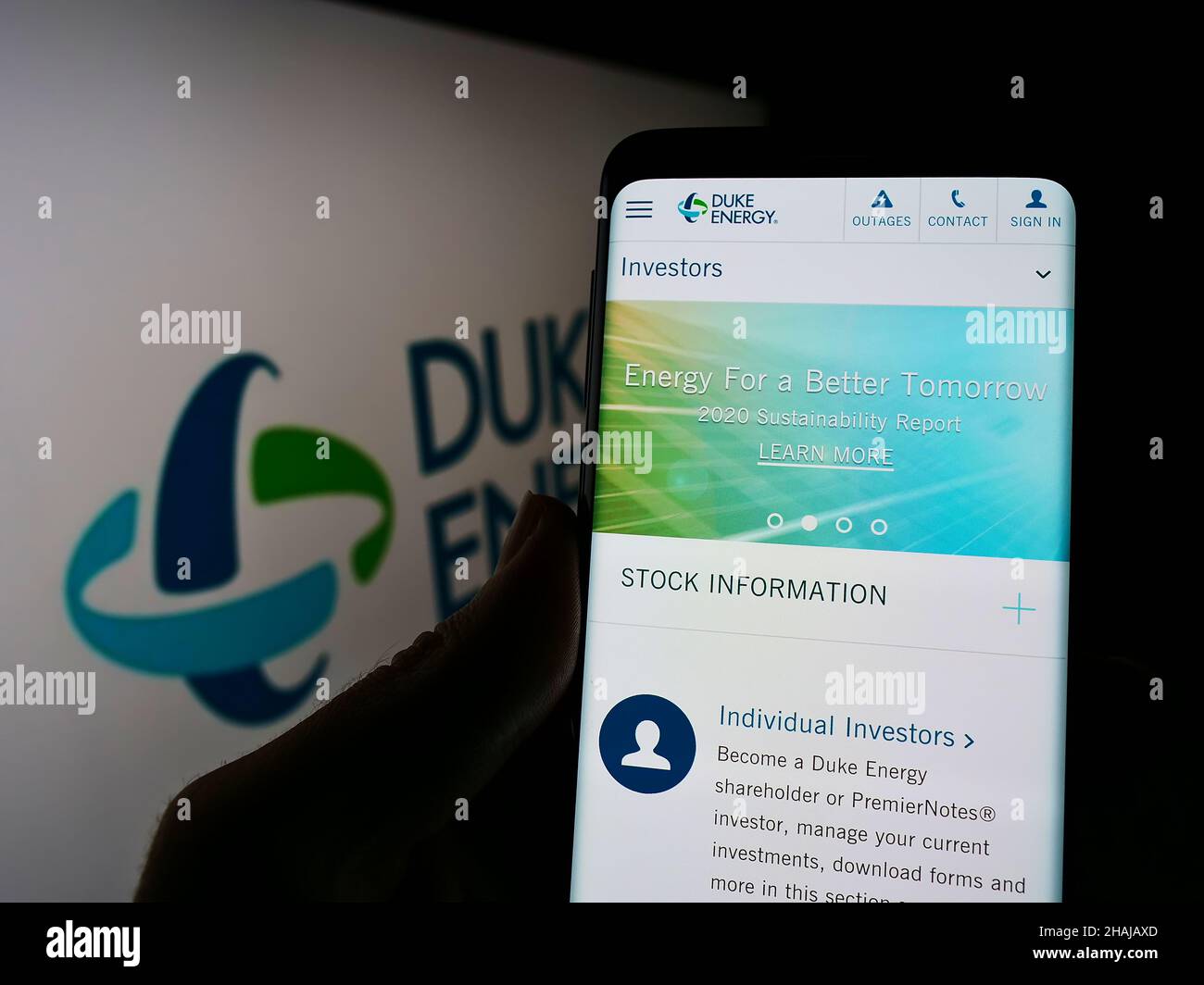 Person mit Mobiltelefon und Webseite des US-amerikanischen Energie- und Gasunternehmens Duke Energy Corporation auf dem Bildschirm mit Logo. Konzentrieren Sie sich auf die Mitte des Telefondisplays. Stockfoto