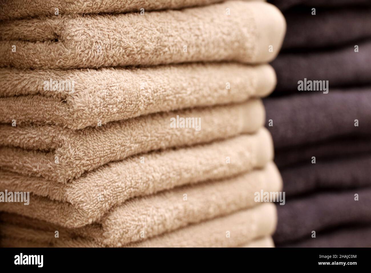 Stapel von Frottee-Handtüchern, selektiver Fokus. Beigefarbenes und dunkles Badetuch in Nahaufnahme Stockfoto