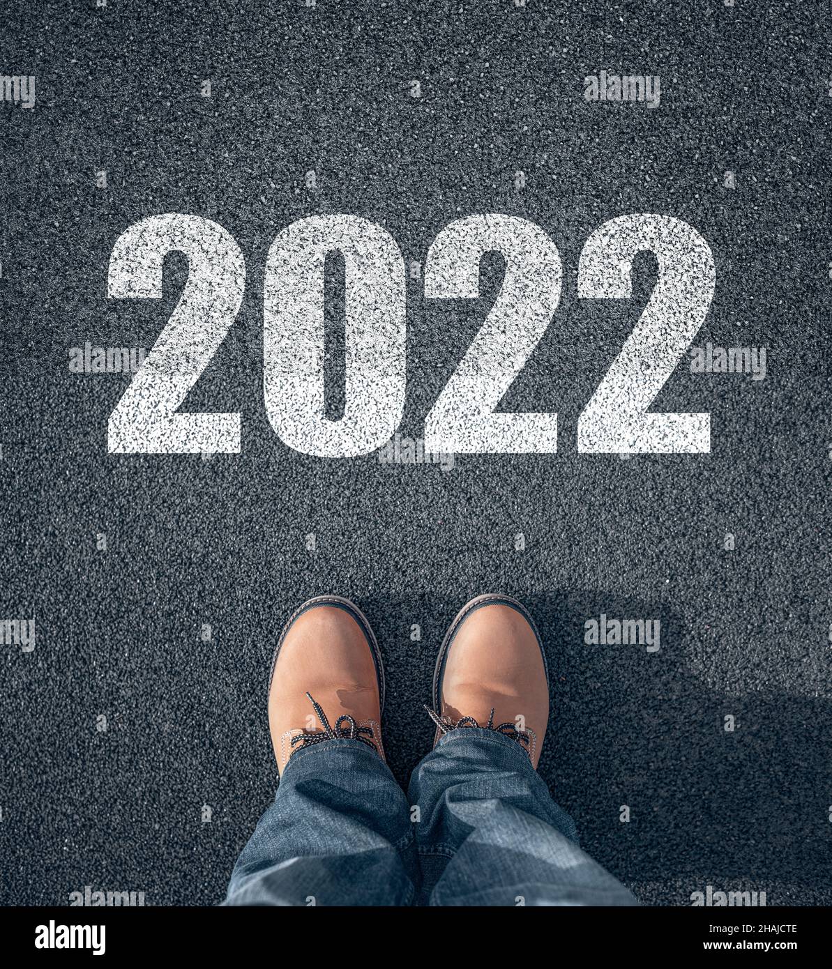Der Mann in Stiefeln macht einen Schritt ins neue Jahr 2022. Stockfoto
