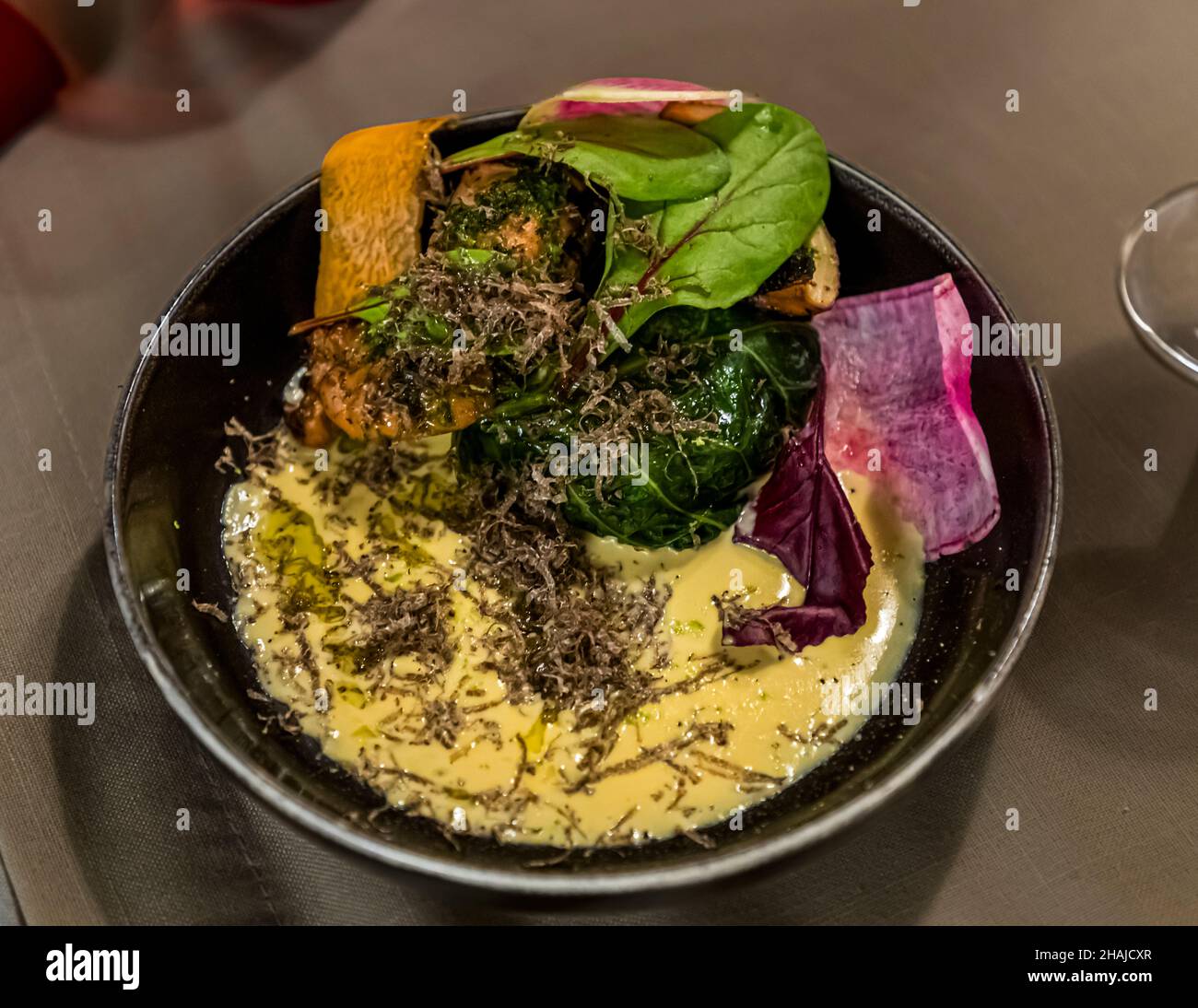 Chard, geriebener schwarzer Trüffel und eine cremige Sauce bilden einen Teller im Restaurant Saint Marc in Aups, Département Var, Frankreich, begleitet von Rettich- und Kürbisscheiben. Stockfoto