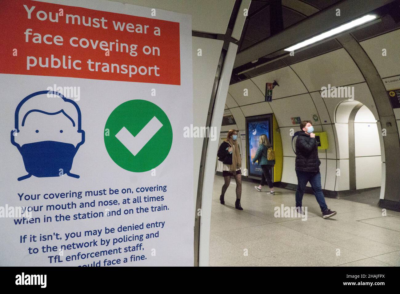 London, Großbritannien, 13. Dezember 2021: Am U-Bahnhof London Bridge halten sich die meisten Passagiere an die Schilder, die alle daran erinnern, dass Gesichtsmasken für öffentliche Verkehrsmittel jetzt obligatorisch sind, sofern sie nicht medizinisch ausgenommen sind. Seit dem Befehl der Regierung, wo möglich von zu Hause aus zu arbeiten, war die Besucherfrequenz an den großen Bahnhöfen um 20 % niedriger als in der Vorwoche. Anna Watson/Alamy Live News Stockfoto