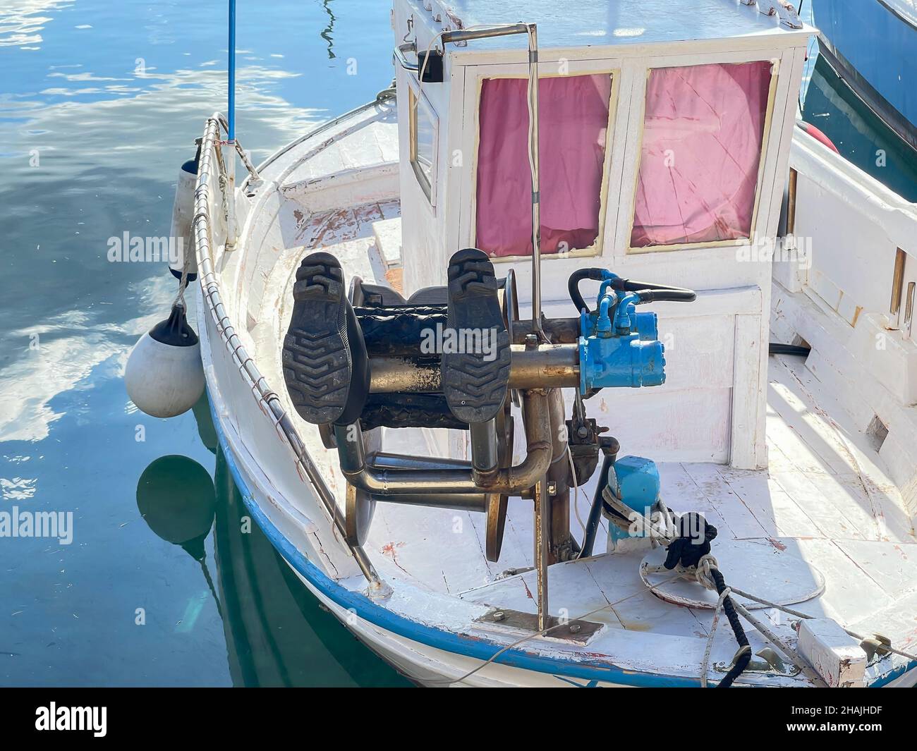 Gummistiefel trocknen auf Bow Winch in einem kleinen Holzboot, das in Ermoupolis, Syros Island, Griechenland, festgemacht ist Stockfoto