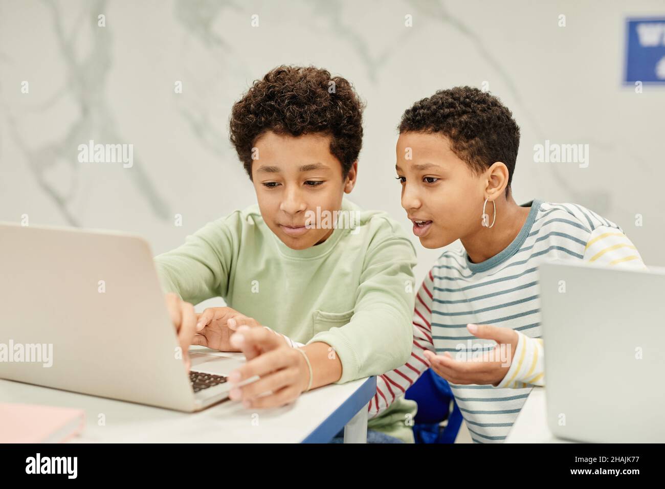 Portrait von zwei Jugendlichen Kindern, die während des Studiums zusammen in Codierungskurs für Kinder sprechen, Copy Space Stockfoto