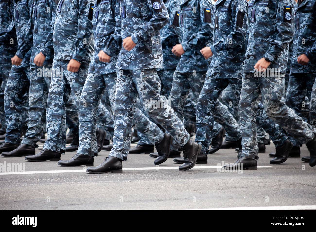 Selektiver Fokus. Bewegungsunschärfe. Moderne militärische Schuhe auf Soldaten. Ein Soldat in Uniform marschiert in der Parade ein. Menschen in der Menge. Stiefel am Fuß. Stockfoto