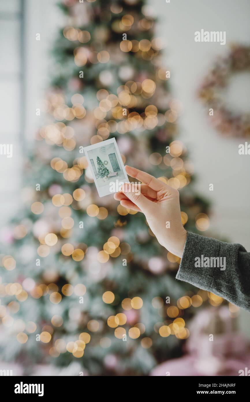 Nahaufnahme der Hand der Frau, die das Bild des geschmückten Weihnachtsbaums hält. Stockfoto