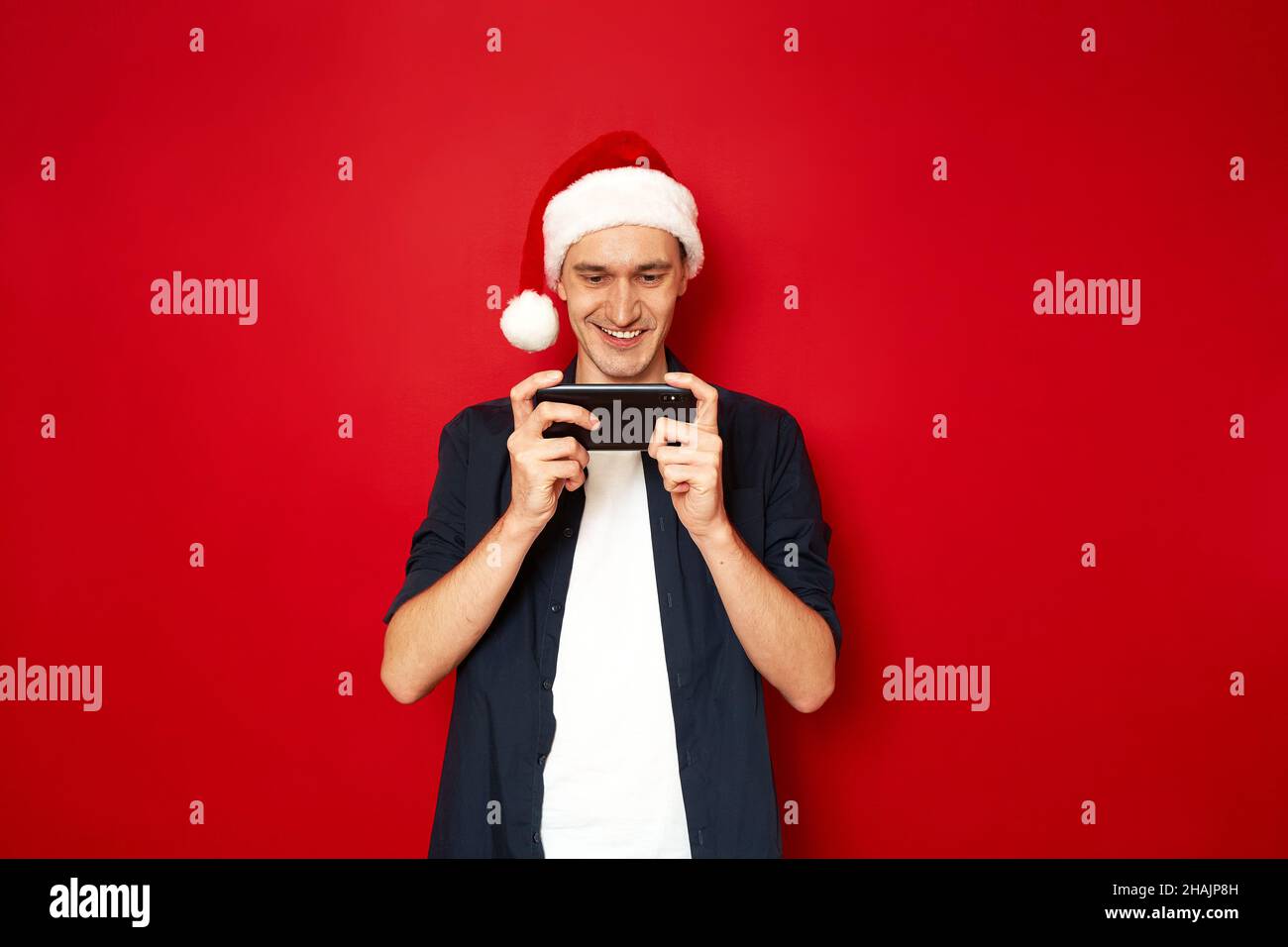 Mann Weihnachten hat Video auf seinem Handy spielen Handy-Spiel in App mit rotem Hintergrund hervorgehoben Stockfoto